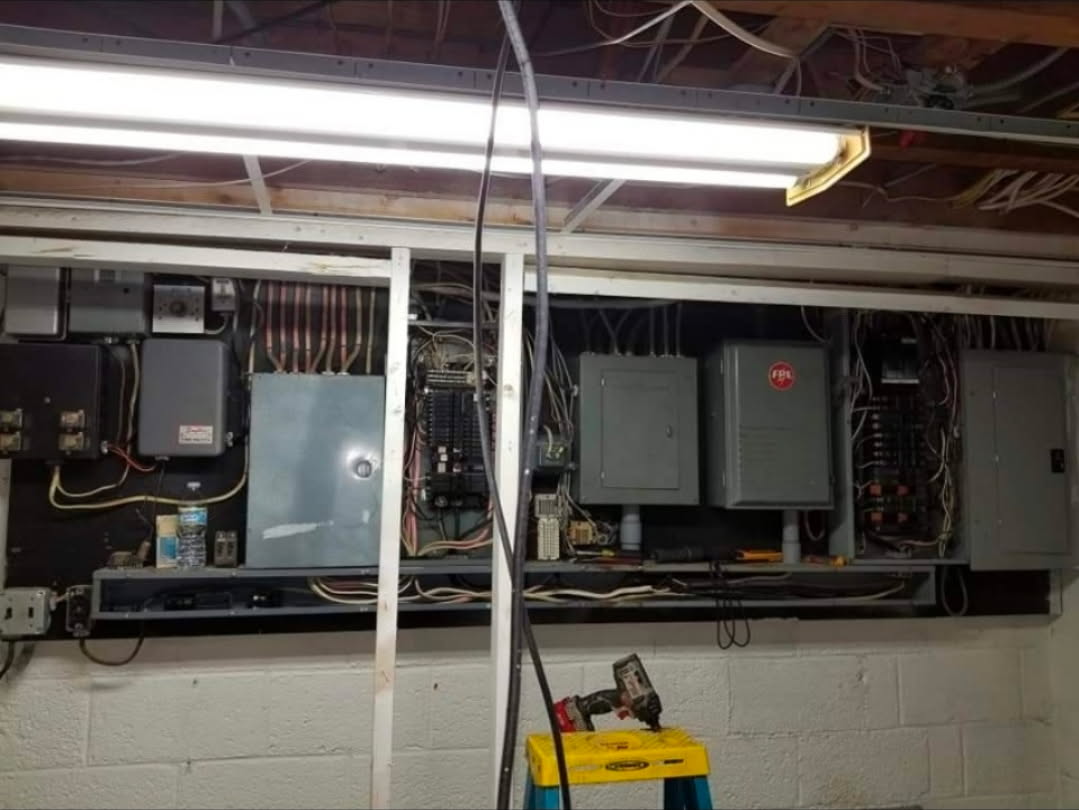 Wall of outdated electrical panels and wiring before removal
